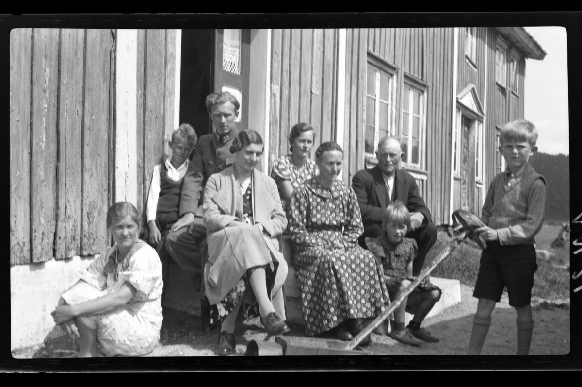 En ukjent kvinne, Hillesund med frue, ukjent, Hilda Sundt, fru Loga, Ånen Loga, ukjent, Lars Peter Sundt sitter på en trapp på Ånen Logas gård i Eiken. Fotografert 1936.