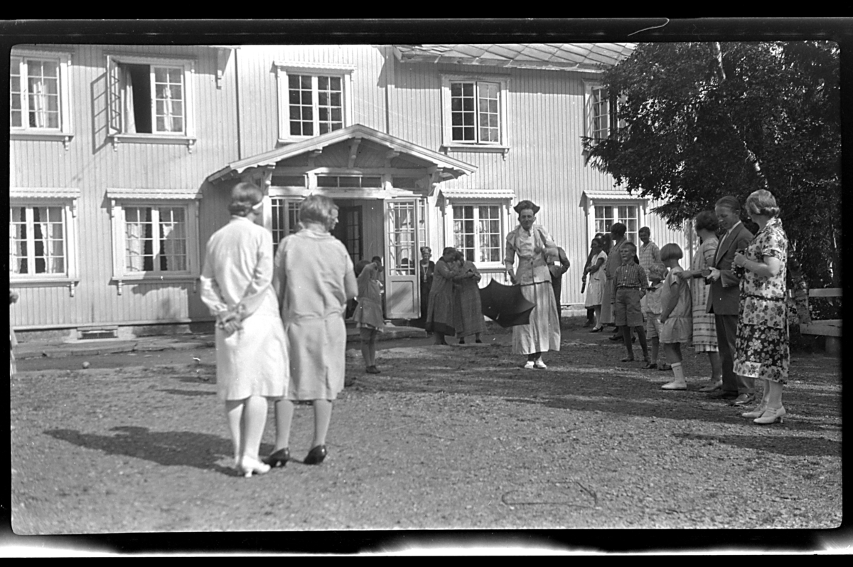 Mange ukjente kvinner og barn er samlet utenfor et stort hus, Tofte. Fotografert 1926.