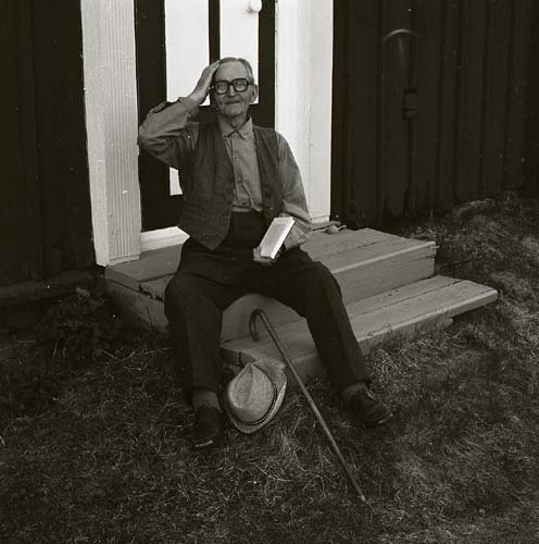 En äldre man med hatt och käpp och en bok i handen sitter på en trappa, Pallars 23 maj 1981.