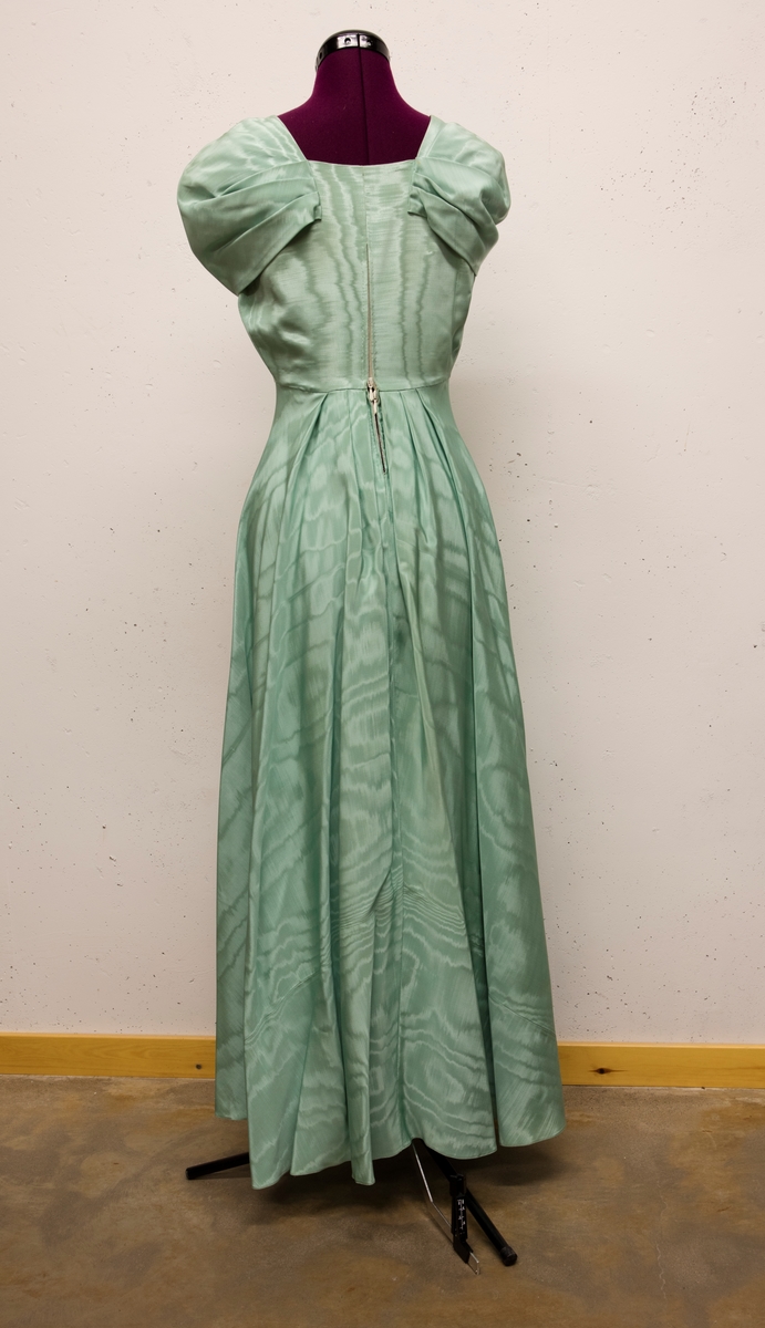 Lång klänning sydd 1947 till Berta Lundell för ett bröllop.
Tyget är så kallad moiresiden. Draperingar över axlarna.