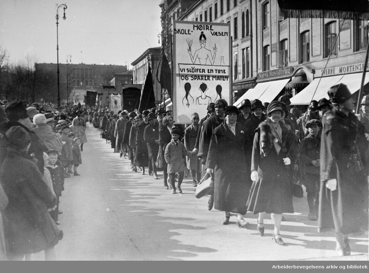 1. mai i Oslo, 1927. Demonstrasjonstoget på vei nedover Karl Johans gate. Parole: Høire skole-væsen. Vi sløyfer en time og sparer maten.