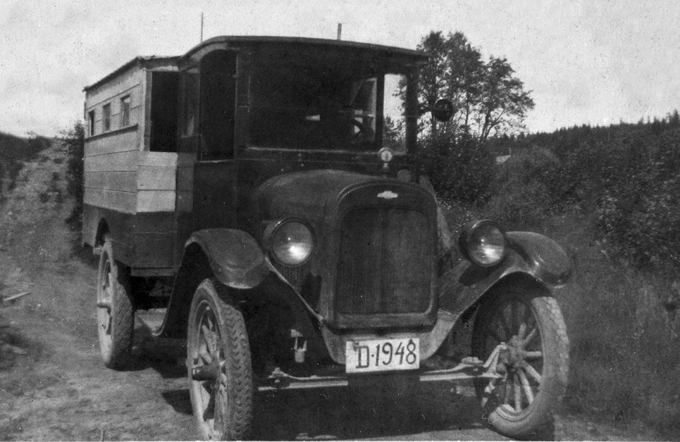 En Chevrolet, trolig 1920-modell, som Klaus Kvernstuen brukte til vare- og  personkjøring tidlig i 1920-åra. Kassa bakpå, der folk kunne sitte, er hjemmelaget. Bildet er tatt ved Kvernstuen i Knapper. Ukjent fotograf.