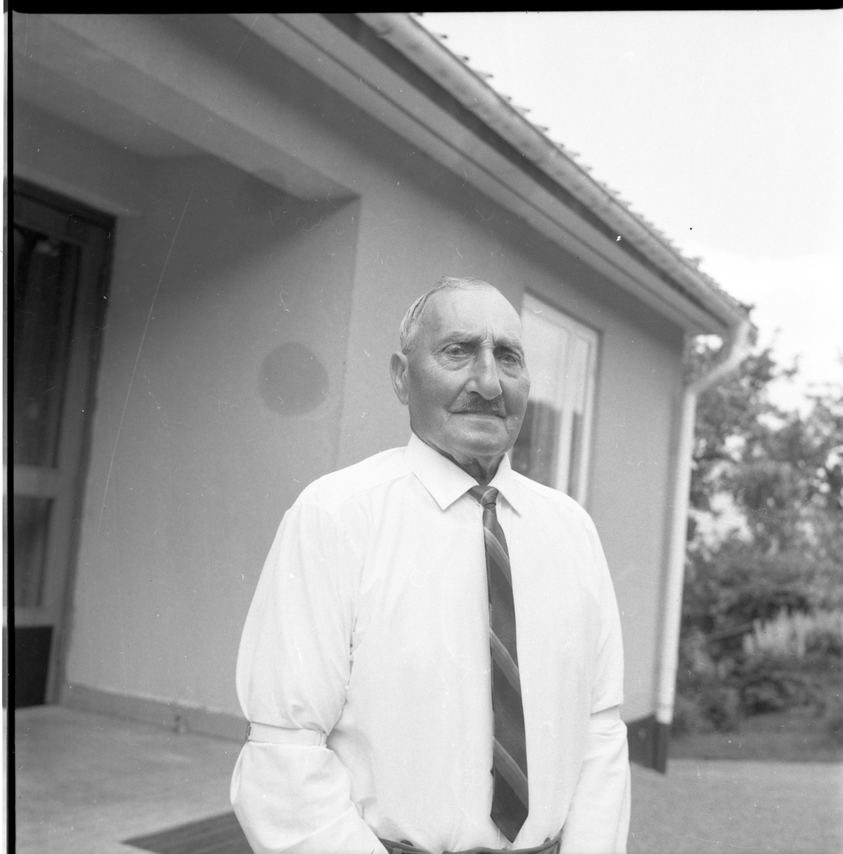 Allvin, en äldre man, stående utanför Mellbyro i vit skjorta och slips på 85-årsdagen.