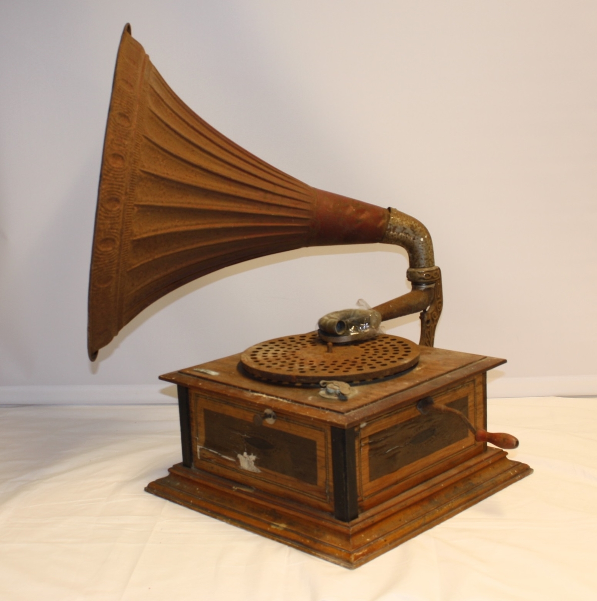 Rektangulær grammofon med sveiv, rund platetallerk og traktforma høgtalar.