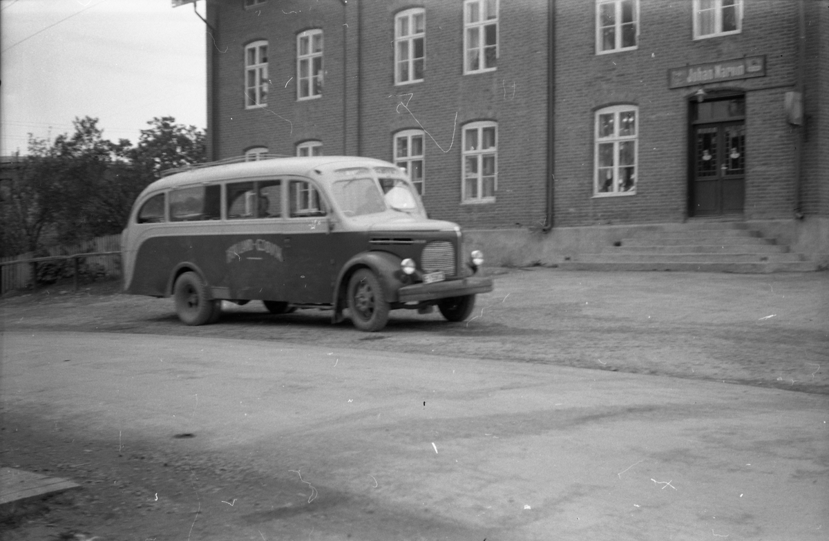 Buss utafor Narums-butikken på Lena, juni 1952. Iflg. informant er bussen av merket Reo Speedwagon. Den tilhørte i 1952 Vestre Toten og Land Bilruter, og ble ved sammenslutningen i 1951 overtatt fra Lauritz Eriksen som drev ruta Hov i Land - Gjøvik. Som ny tilhørte bussen Reinhard Quale på Lista.