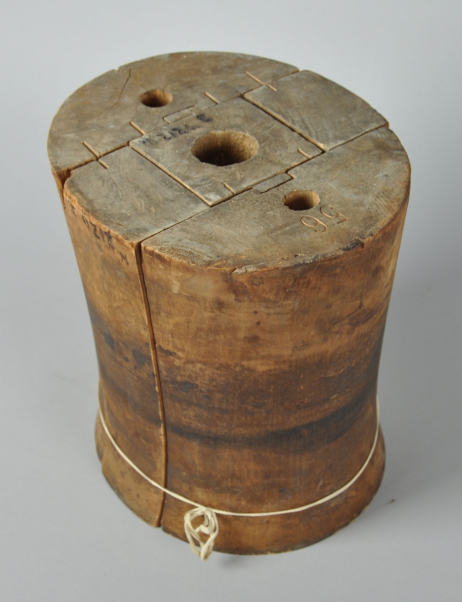 Sylinderformet hatteblokk hvor midtpartiet er innsnevret. Består av fem deler som holdes sammen med et bånd. På undersiden av formen er det hull for skruefeste på tre av delene.
