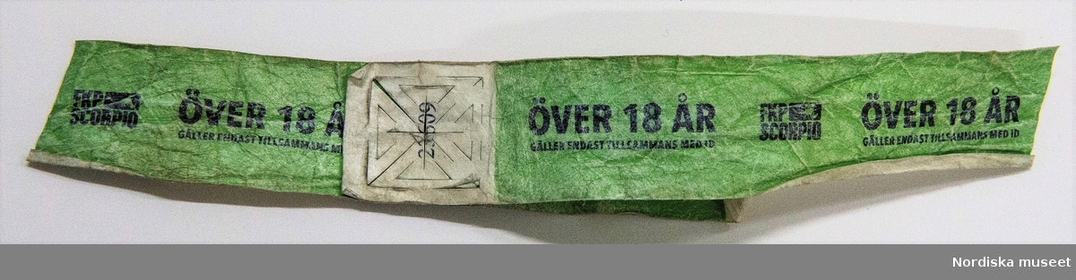 Armband av grönt pappers-/plastmassa. Tryck med svart text : "ÖVER 18 ÅR / Gäller endast tillsammans med ID / FKP Scorpio" samt FKP Scorpios logga (skorpion). 
Avklippt
/Leif Wallin 2017-08-17