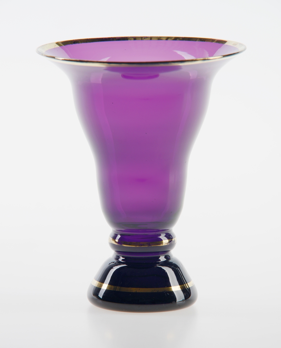 Konsik glassvase med bølgete form og glatt kant. Dekorert med gullforgyldning rundt kanten, stetten og foten.