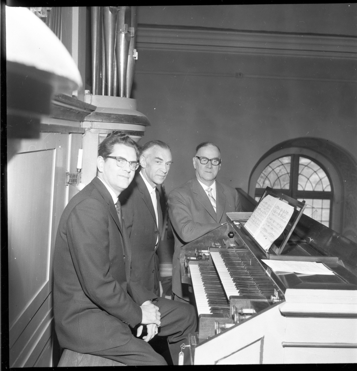 Vid orgeln i Skärstad kyrka sitter musikdirektör Karl-Olof Robertson från Huskvarna, kantor Georg Sandqvist och domkyrkoorganisten i Växjö domkyrka. Det är återinvigning av läktarorgeln i Skärstads kyrka efter om- och tillbyggnad av orgeln år 1962.