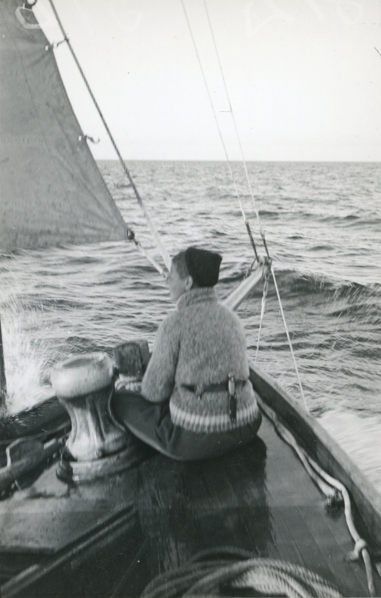 En ung kvinna i fören på en segelbåt.