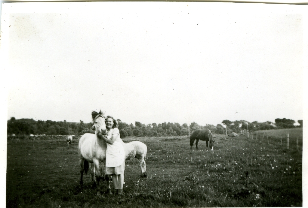 Solveig Holen g. Svalestad (12.1.1928 - ) ser til hestane som går på beite.