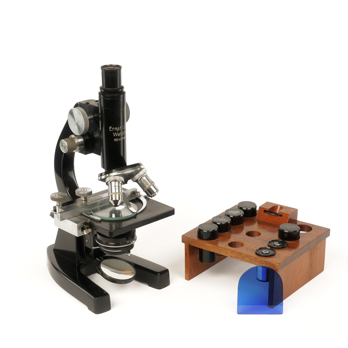 Mikroskop i trekasse med dør, håndtak og lås med nøkkel og div utstyr til mikroskopet.