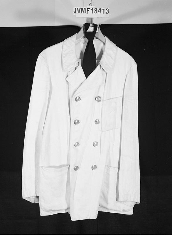 Hel sommaruniform av vitt linne, bestående av dubbelknäppt kavaj, väst och byxor.
Kavajen och västen har silverfärgade knappar.
Till uniformen hör även en svart slips med samma inventarienummer.