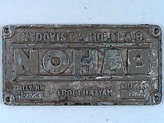 Rektangulär skylt av förnicklad mässing med text i relief mot räfflad botten.
Från elloket SJ Da 898.
NOHAB tillv nr. 2264, i uppgifter från Nohab anges tillv. år till 1955 men på skylten står det 1956.
