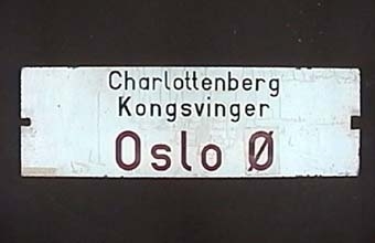 Dubbelsidig vändbar plåtskylt med svart och röd text på vit botten.
På ena sidan står det:
"Charlottenberg
Kongsvinger
Oslo Ø"

På andra sidan:
"Oslo Ø
Kongsvinger
Charlottenberg"