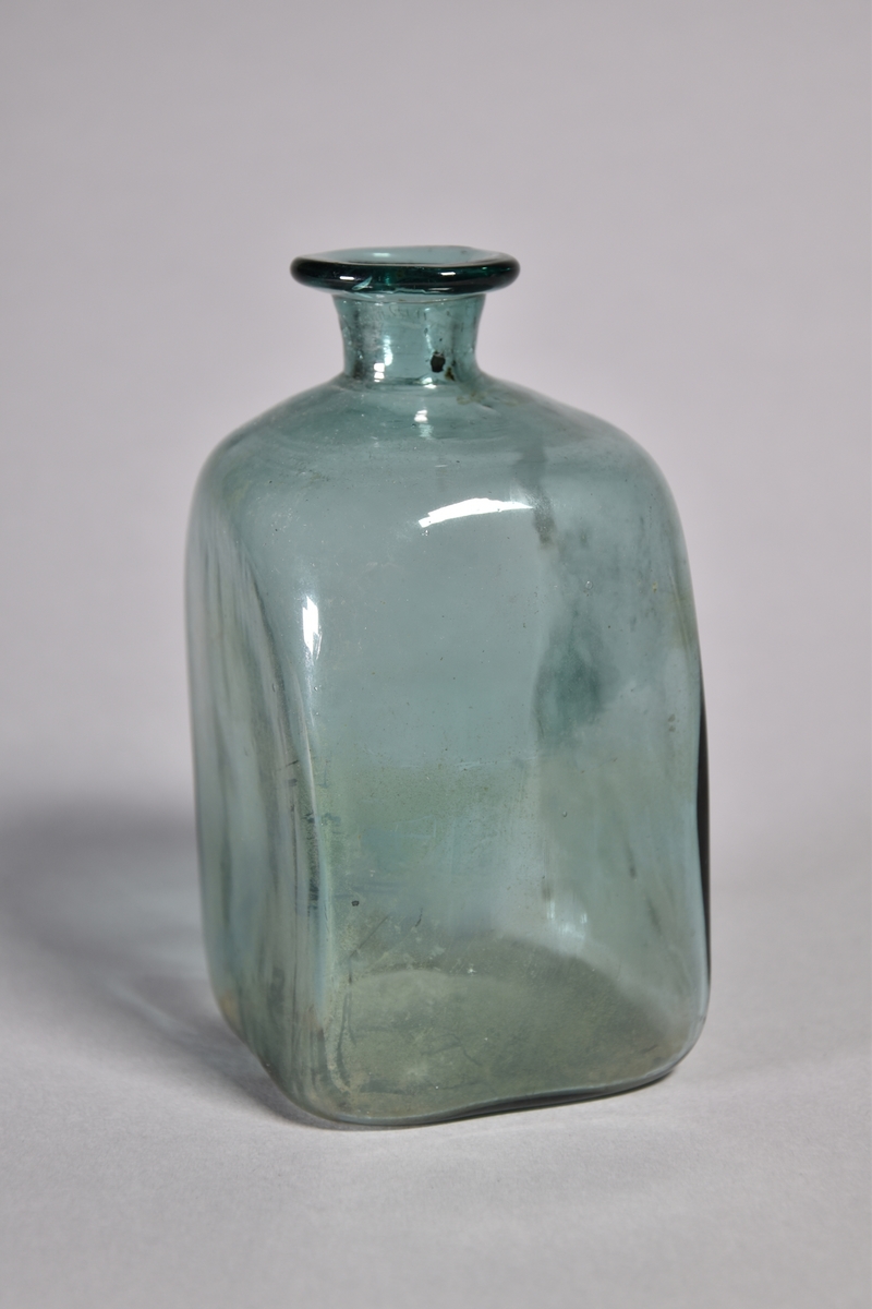 Flaska av grönt glas, kvadratisk, kort hals med utvikt mynning.