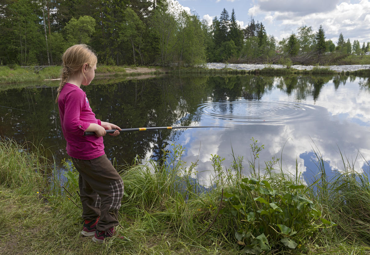 Ung jente fisker i barnas fiskedam