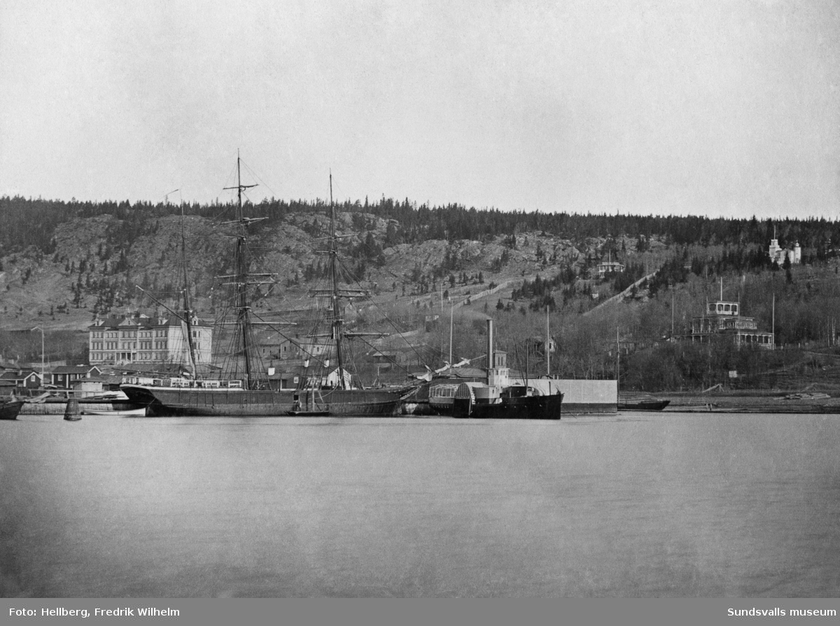 Hamnen med ett segelfartyg och hjulångaren "Swartvik". På bilden till vänster Sundsvalls lasarett, i mitten på bilden bakom hjulångaren syns ett torn vilket hör till kallbadhuset och till höger på bild syns Tivoli. Bildtext i allbum "Hamnen, Lasarettet, badhuset och Tivoli i bakgrunden."