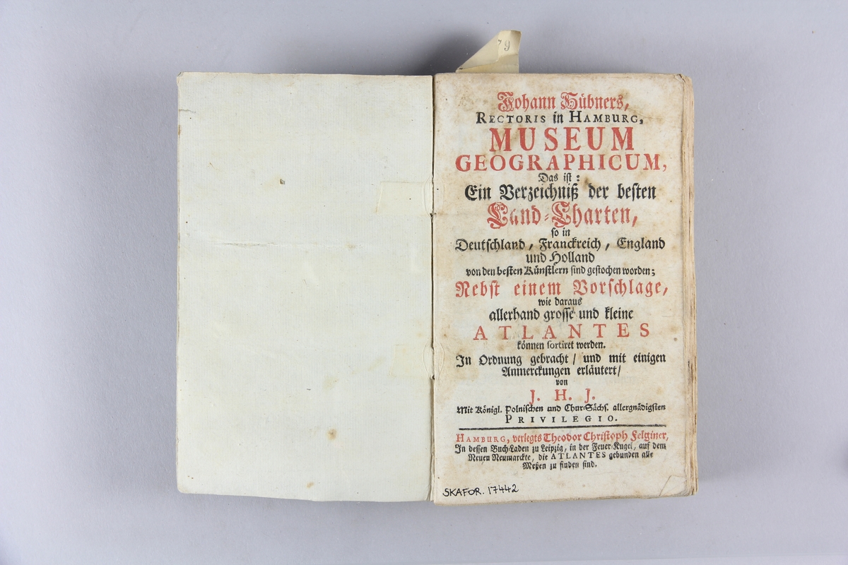 Bok, pappband, "Museum Geographicum". Pärm av blågrått papper, skuret snitt. Blekt rygg.