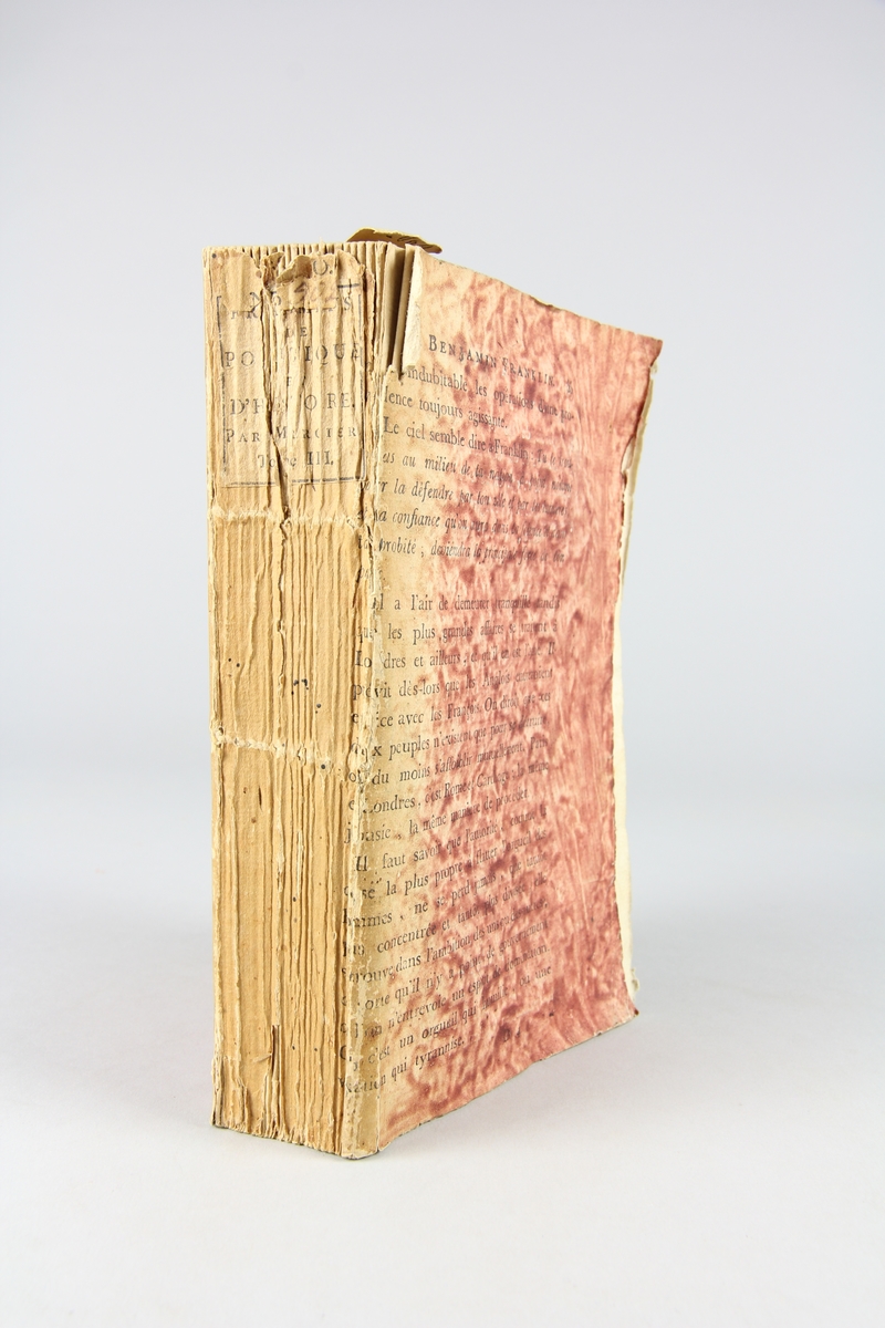 Bok, "Fragments de politique et d´histoire", del 3, tryckt 1792  i Paris. Pärmar av rödmönstrat papper med tryckt text ur annan bok. Skuret snitt. På ryggen tryckt etikett med volymens titel och samlingsnummer.