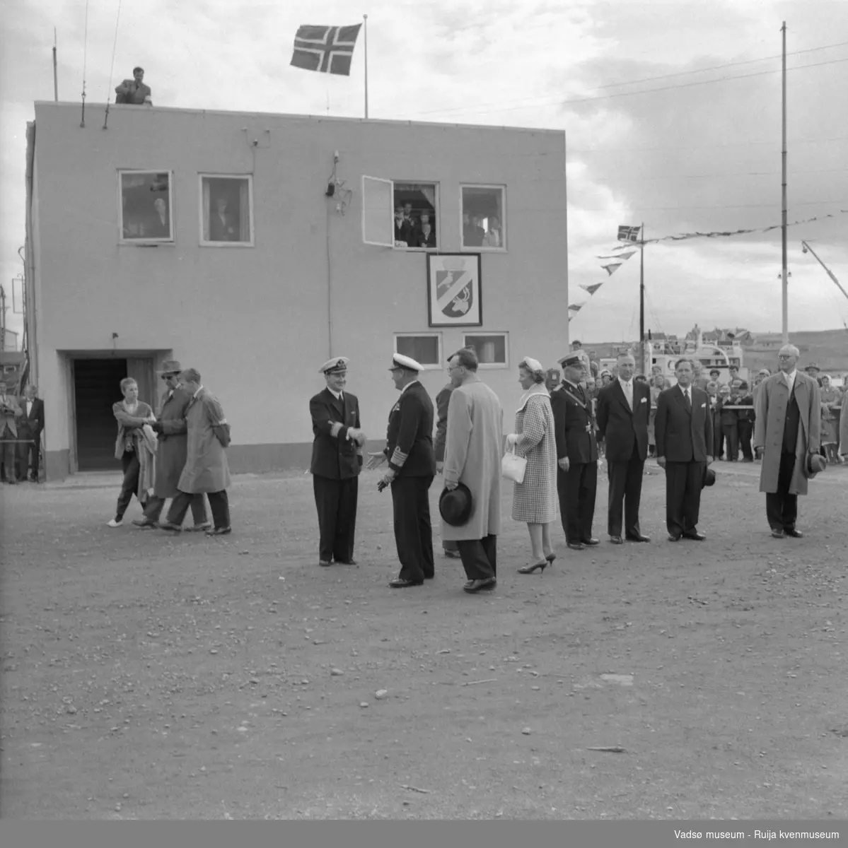 Vadsø juli 1959. Kongebesøk. Kong Olav og prinsesse Astrid blir tatt imot av kommunens delegasjon. Prinsesse Astrid hilser på ordfører Anders Aune, kong Olav står til høyre for Astrid