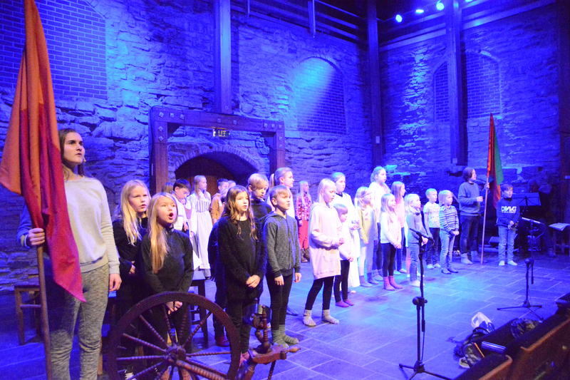 Mange barn og ungdommer står på scena i Aulaen på Domkirkeodden og synger.