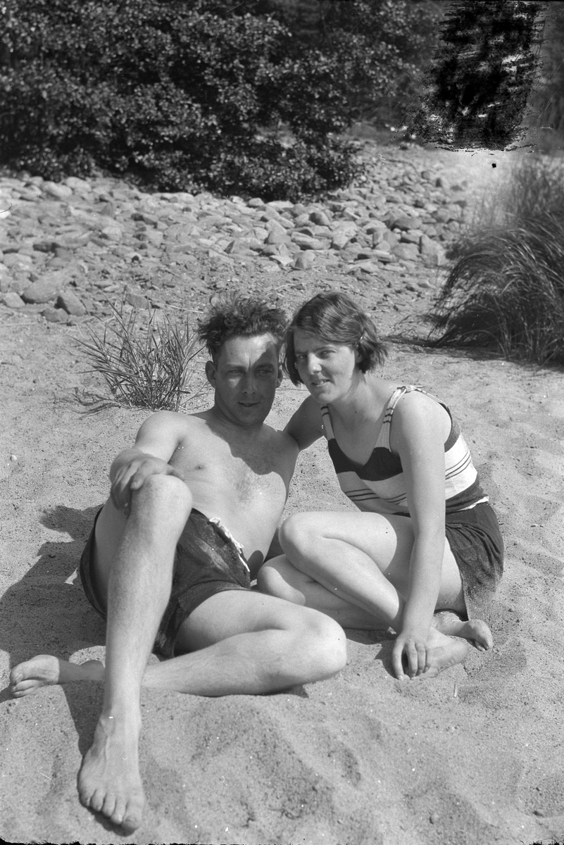 En man och en kvinna fotograferade på en strand. Troligen är det Harald Olsson och Lizzie Skoglund.