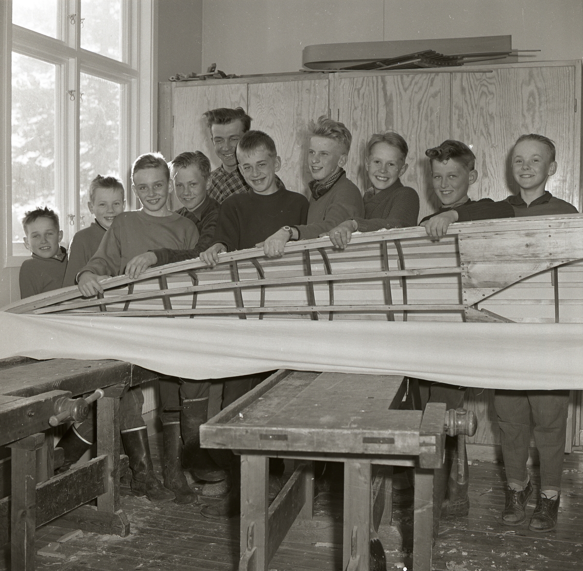 Interiör från slöjdsal. Ett gäng ungdomar bygger en kanot.