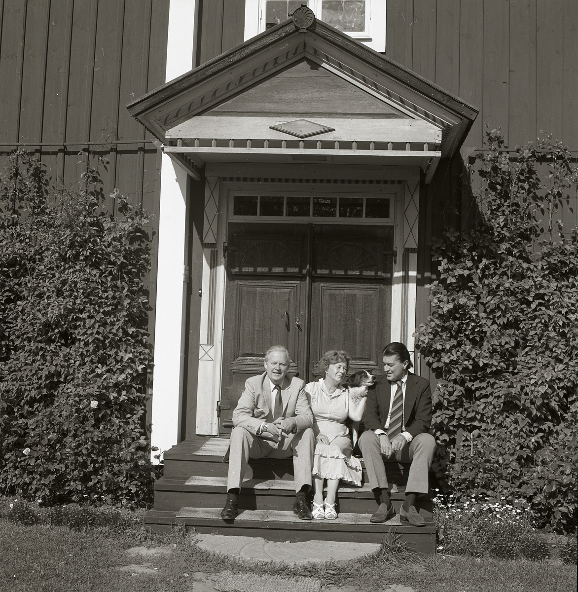 Adéle sitter tillsammans med två män och en hund på trappan till Sunnanåker, 3 september 1982.
