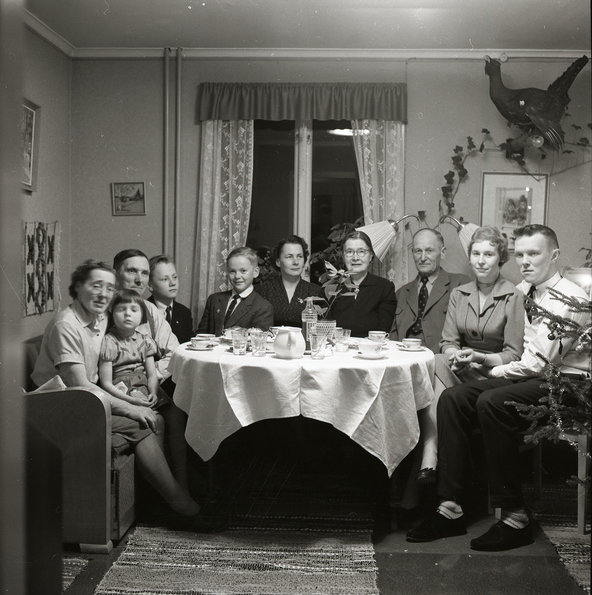 En samling människor sitter vid ett bord och fikar.
