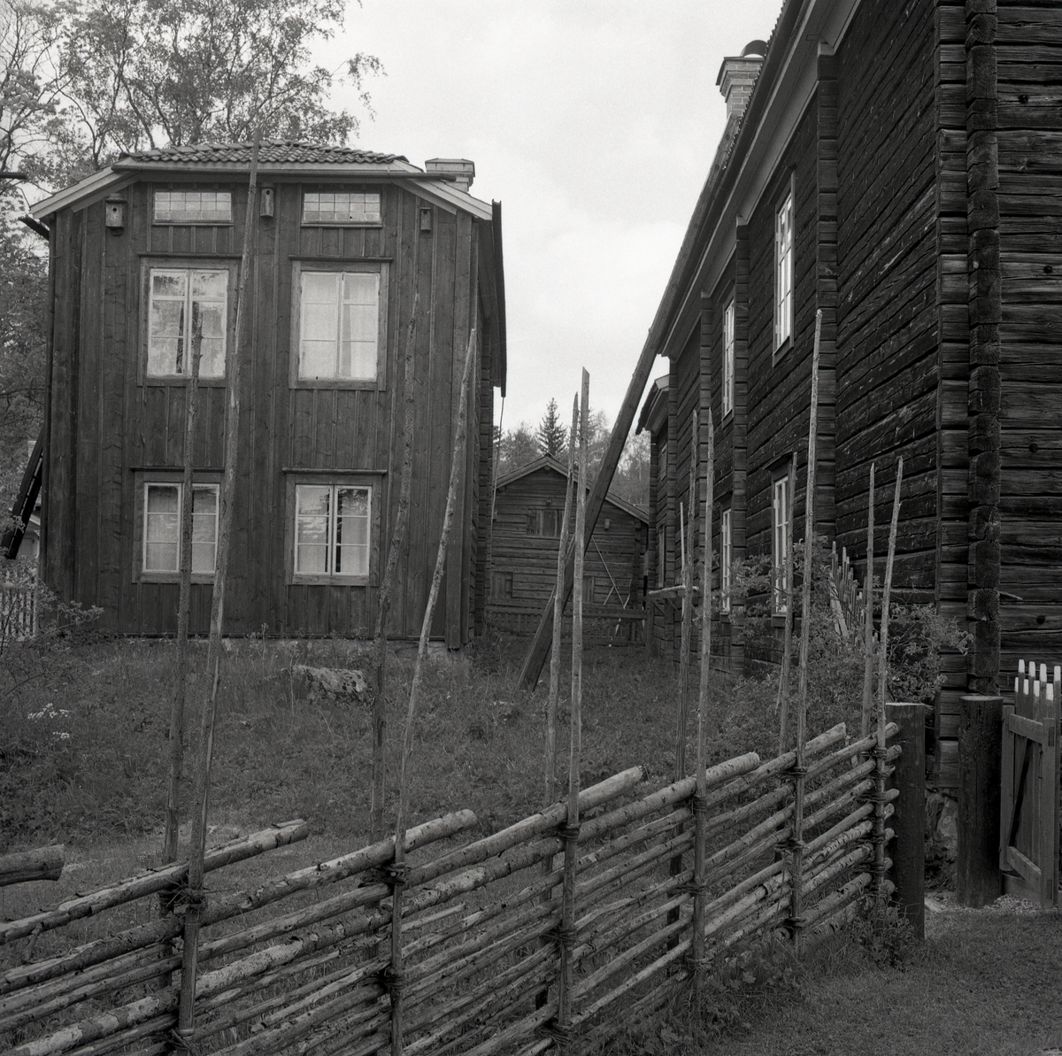 Några timrade hus står på en gård vid Hembygdsbyn, 1975.