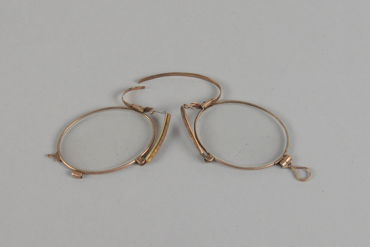 Lorgnett bestående av to brilleglass med nesebøyle av metall. Nesebøylen er brukket.