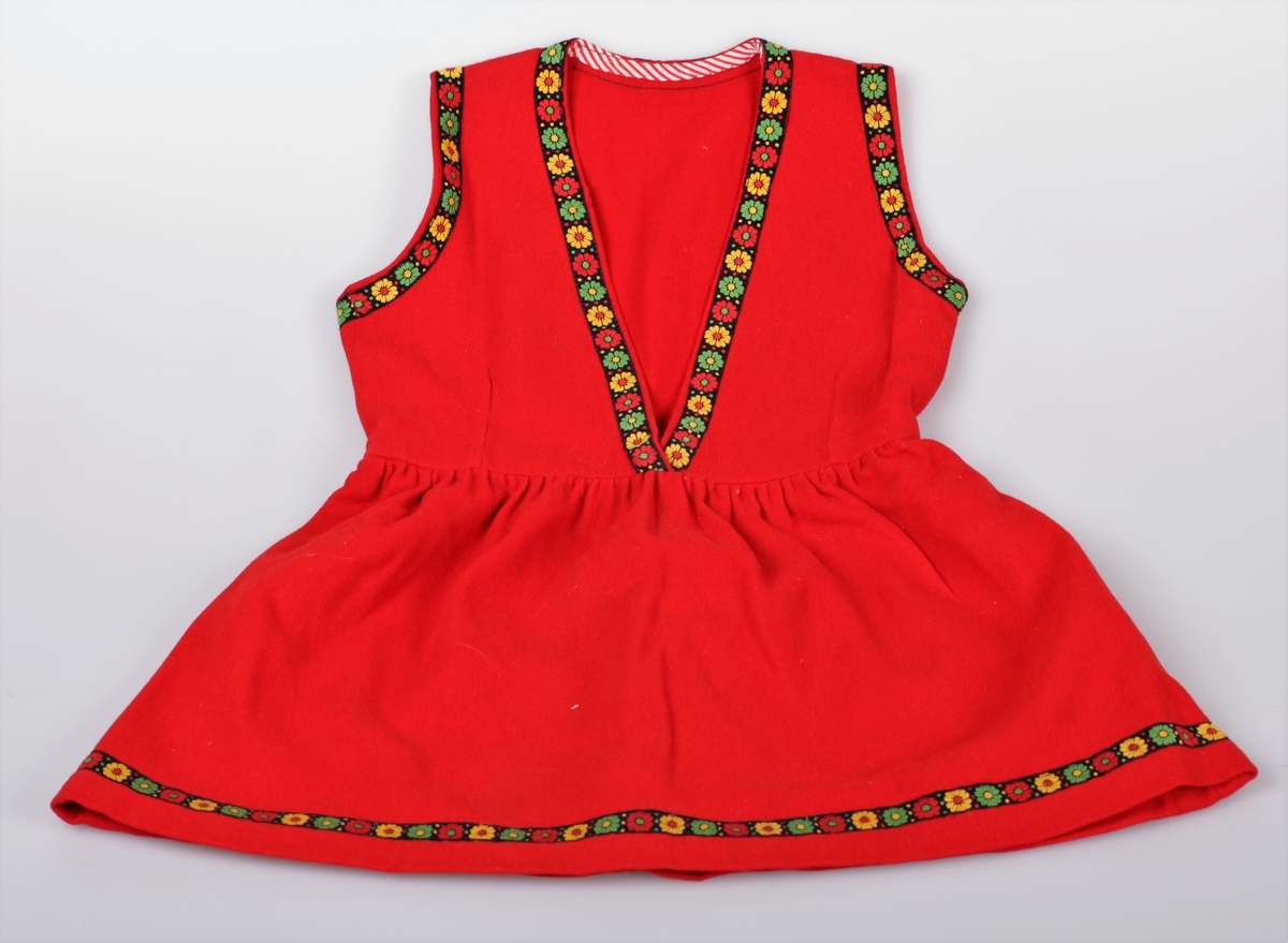 Festdrakt sydd av rød ullfilt. Den har et formsydd liv, og skjørtet har god vidde. På skjørtet og livet er det påsydd et dekorbånd. Drakta har samme stil som TM-15841. Det hører med en kyse til antrekket, og den er registrert som TM-15847. Tilhørende skjorte til kjolen er registert som TM-15845. Fire søstre hadde like ens hjemmessydde kjoler som dette.