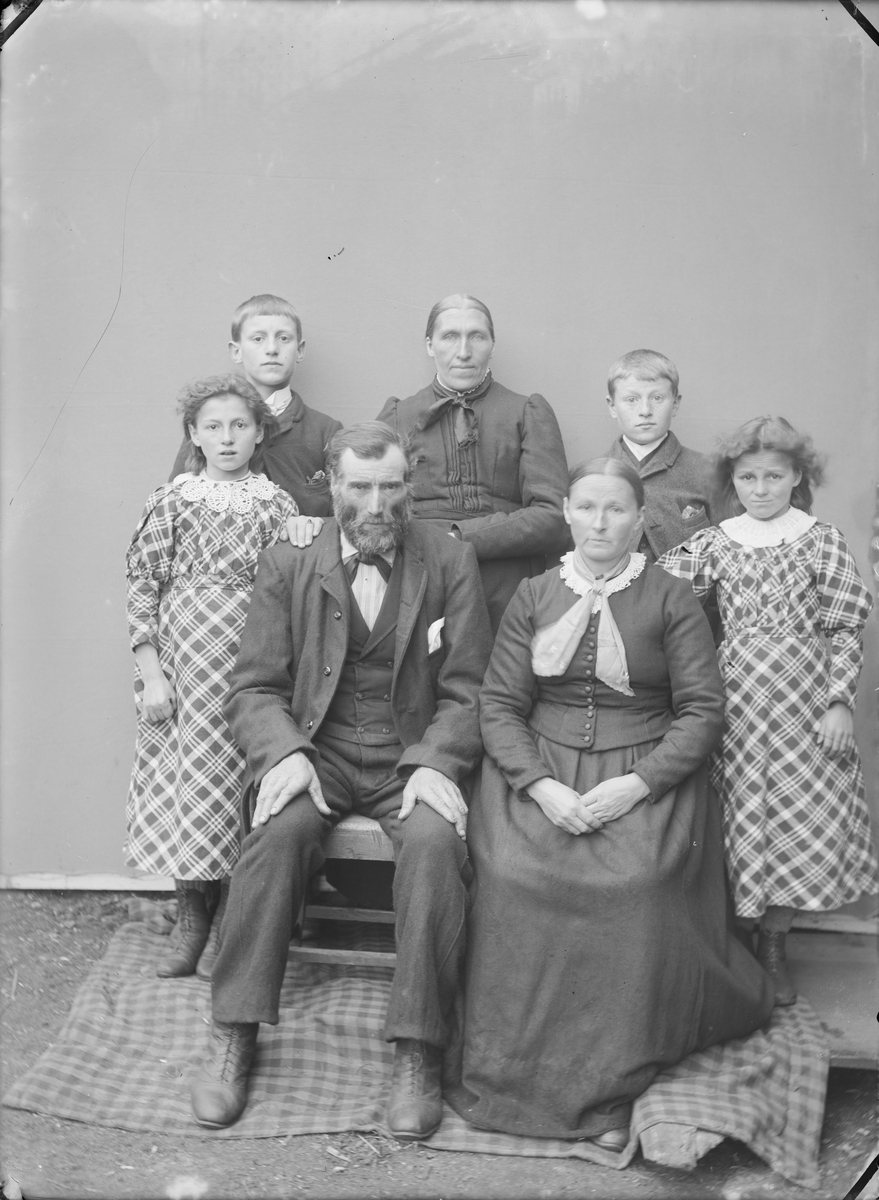 Familiebilde med antatt 3 generasjoner. Atelierfoto med familiebilde fra garden Gjershaug, Verma i Romsdal. Bildet viser bestemor, foreldre, to jenter og to gutter.