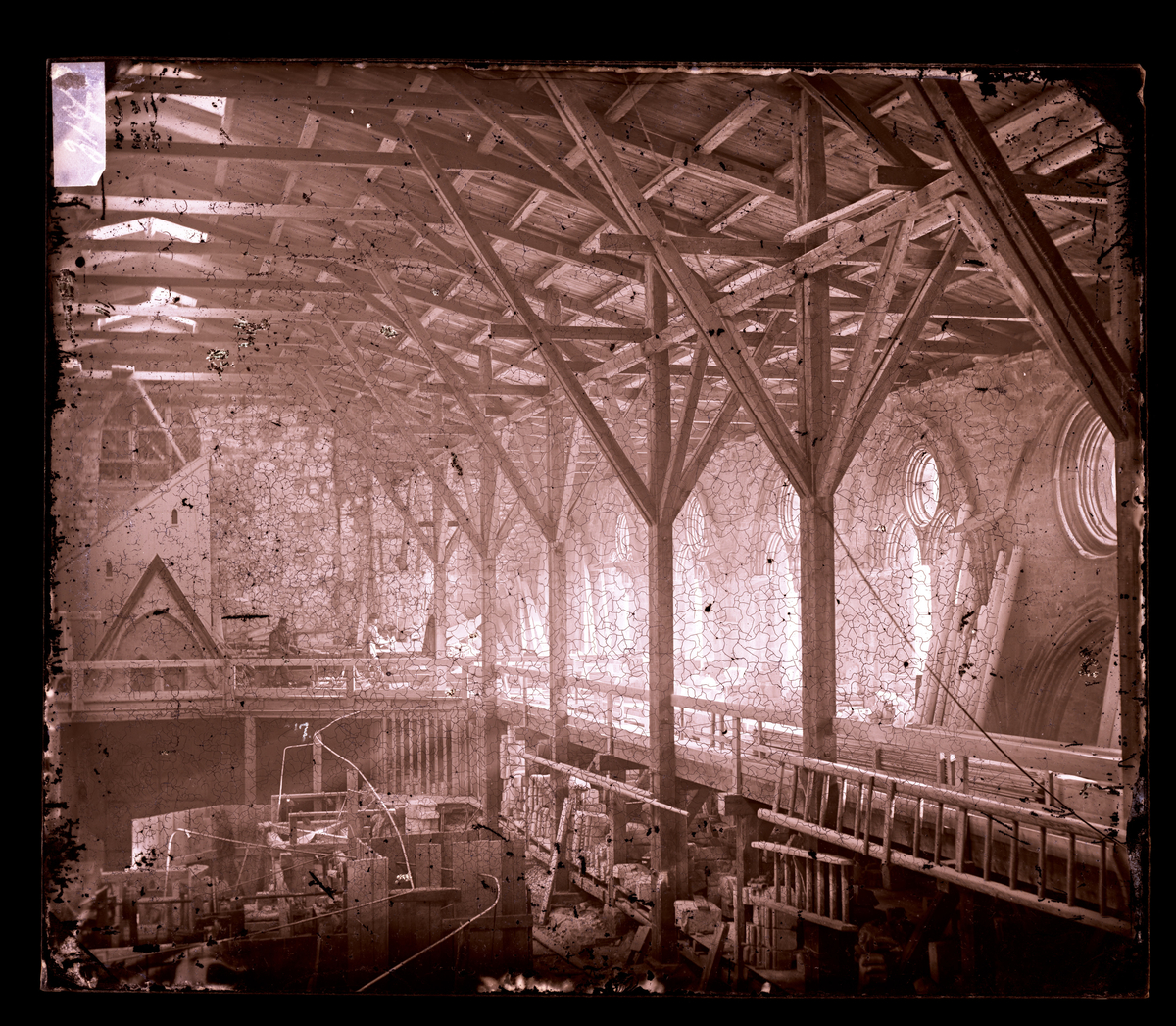 Steinhuggerverksted i skipet i Nidarosdomen (verksted fra 1878-1914). To menn arbeider i stillaset til høyre for spissbuen.