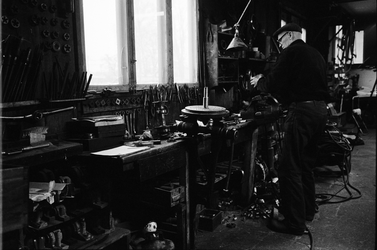 Fabrikör Karl-Gustav Johansson reparerar en pelletskvarn, Enköpings Kvarnstensfabrik, Bangårdsgatan 13, Enköping, Uppland 1984