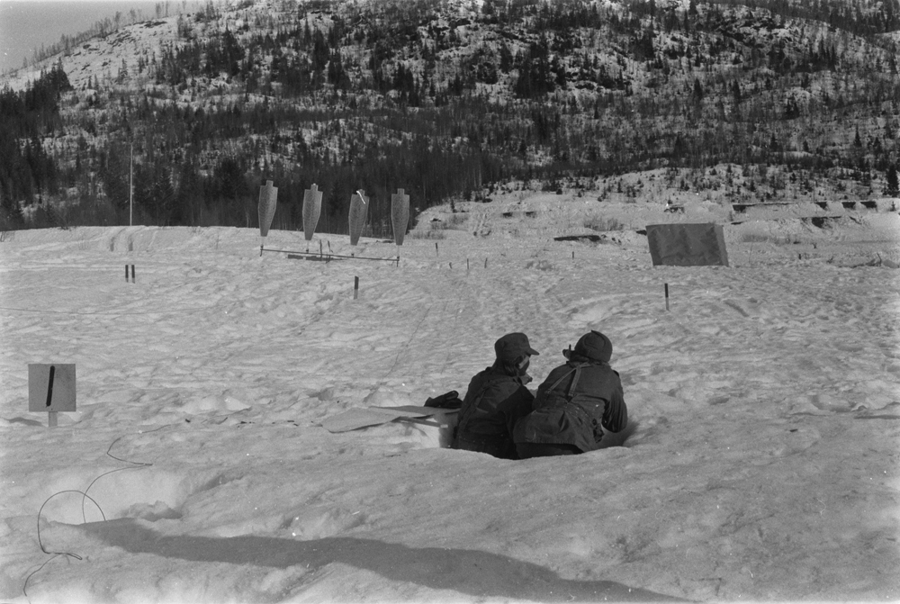 Repetisjonsøvelse på Drevjamoen. 
2 soldater i skyttergrav på skytterfelt, silhuetter i bakgrunnen.