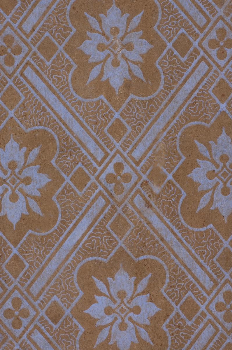 Tapetprov med tryckt mönster i ljust, blått och brunt.
