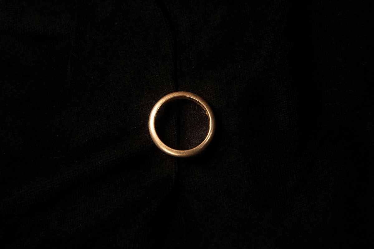 Fingerring av gulddouble, liggandes i en rund smyckesask med lock. Asken har ett marmorerat mönster, svart med roströd botten. Locket är rostrött med små inpräglade streck. Eventuellt hör inte de olika askdelarna till varandra från början.
