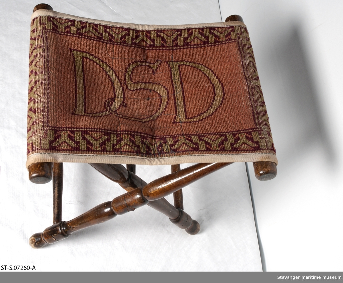 Taburett i tre og tekstil, med DSD logo.