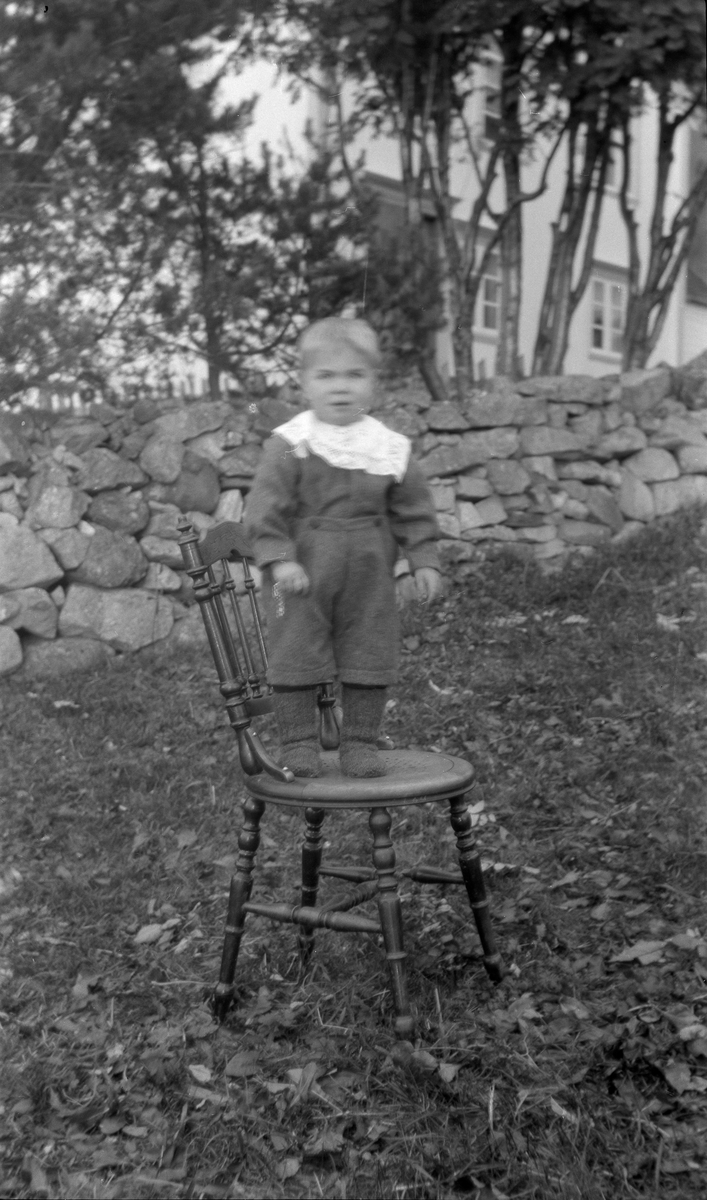 Portrett av gutt stående på stol utendørs.
