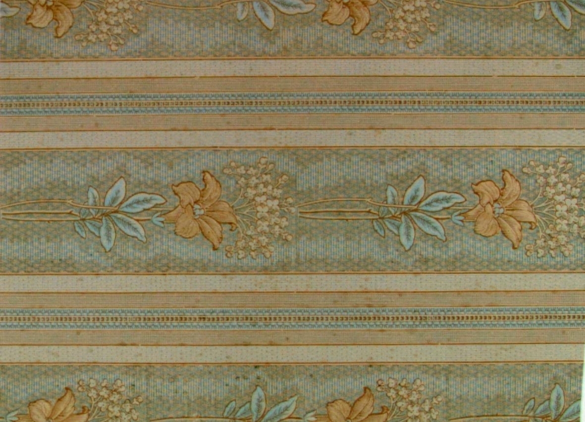 Randmönster med varierande bårder omväxlande med en vertikalt utsträckt lilja. Tryck i chokladbrunt och ljusblått på ett ofärgat papper. Textilimiterande.