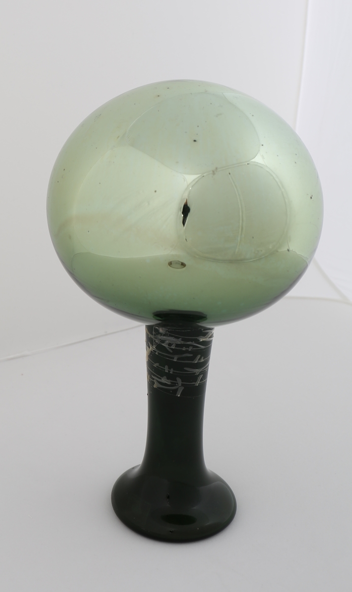 Blåst glasskule med sylindrisk stuss. Grønfarga glas med reflekterande belegg på innsida. Stussen skal stå nedi ein vaseforma stett av grønt glas, med rett avskoren munningsrand, tilnærma sylindrisk korpus og utvida i ein sylindrisk fot.