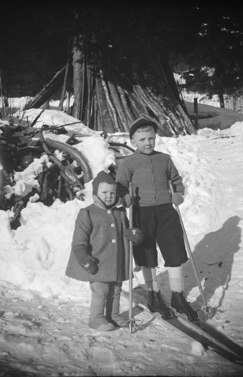 Portrett av to barn, gutt på ski og en pike ved siden av