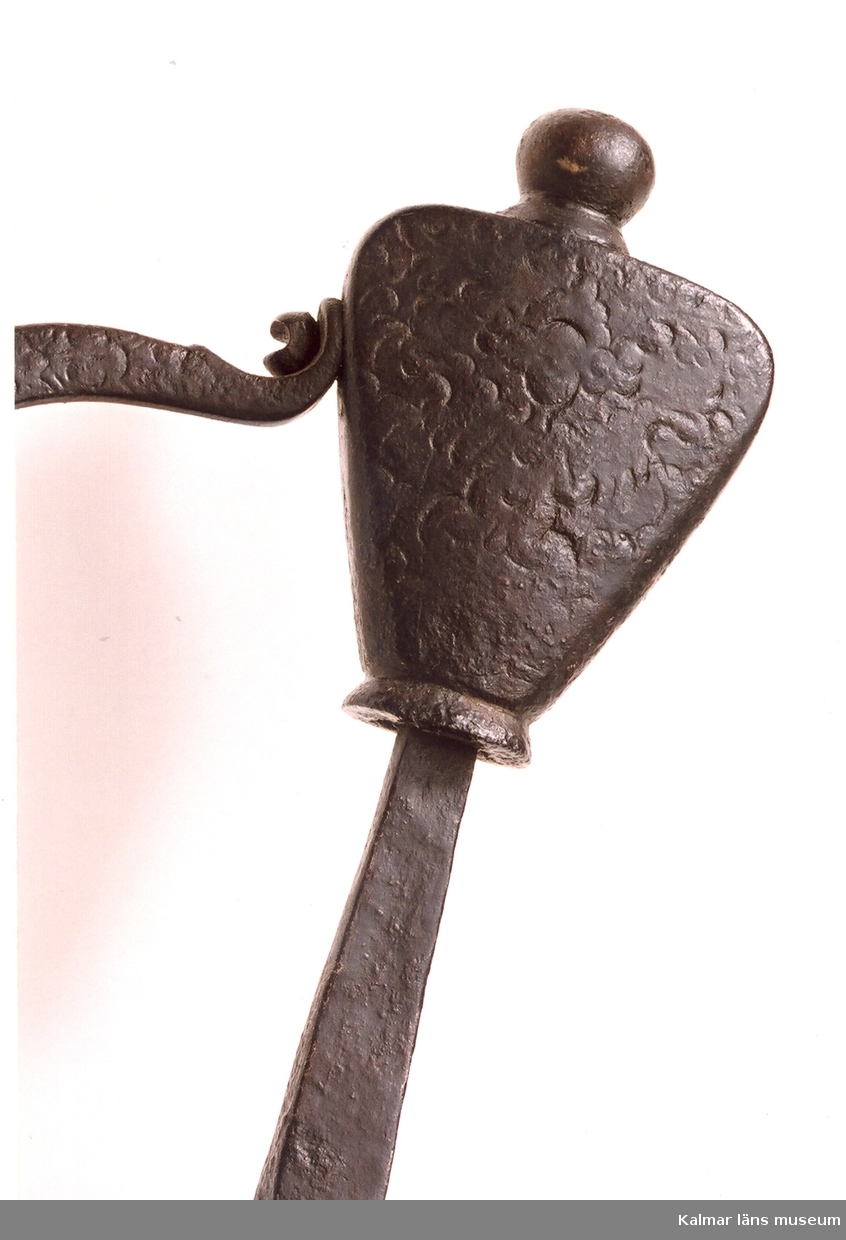 KLM 6589. Värja, av järn. Rak tveeggad klinga med linsformig genomskärning. På båda sidor återfinns Johannes Wundes (Solingen 1560-1610) stämpel (ett krönt huvud), på terssidan dessutom ulvmärke och ett riksäpple med dubbelt kors och SS. Fäste av järn med punsad ornering (serafhuvud, blad och blommor). Genombruten parerplåt, bakre parerstång, handbygel och tumring i ett stycke. Flat päronformig knapp, ornerad. Datering, från 30-åriga krigets tid.