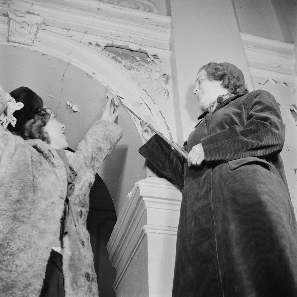 Två kvinnor visar flagnad färg, Östgöta nation inför restaurering, Uppsala 1946