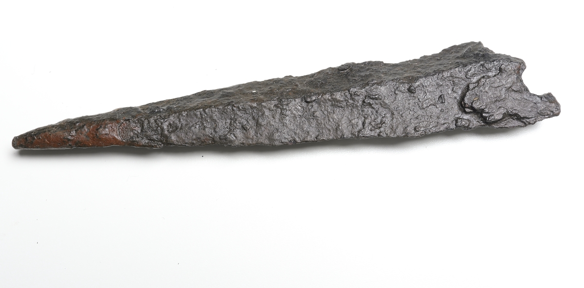 Fragment av ett dolkblad med rombiskt tvärsnitt, där endast spetsen är bevarad.