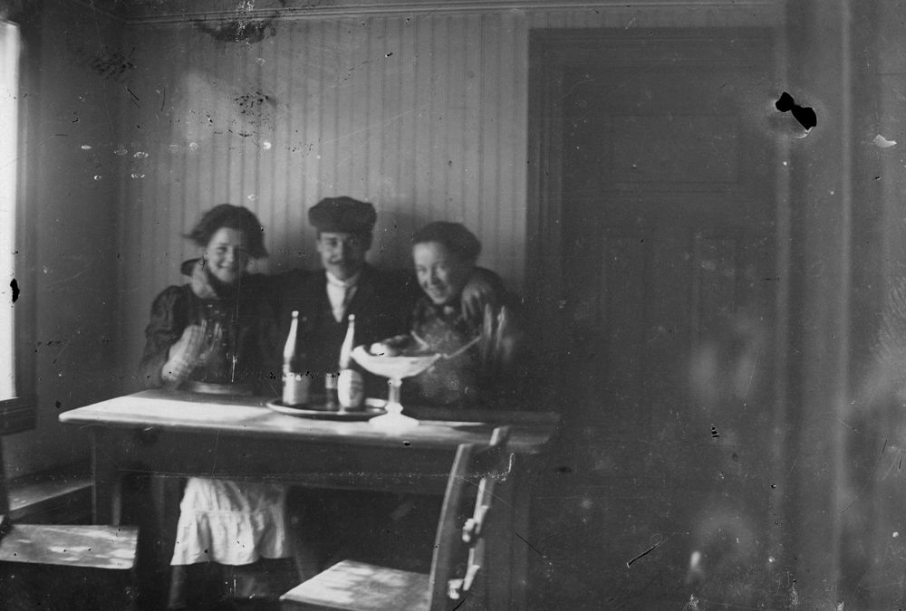 Leirfjord. Tre unge mennesker fotografert inne ved et bord.