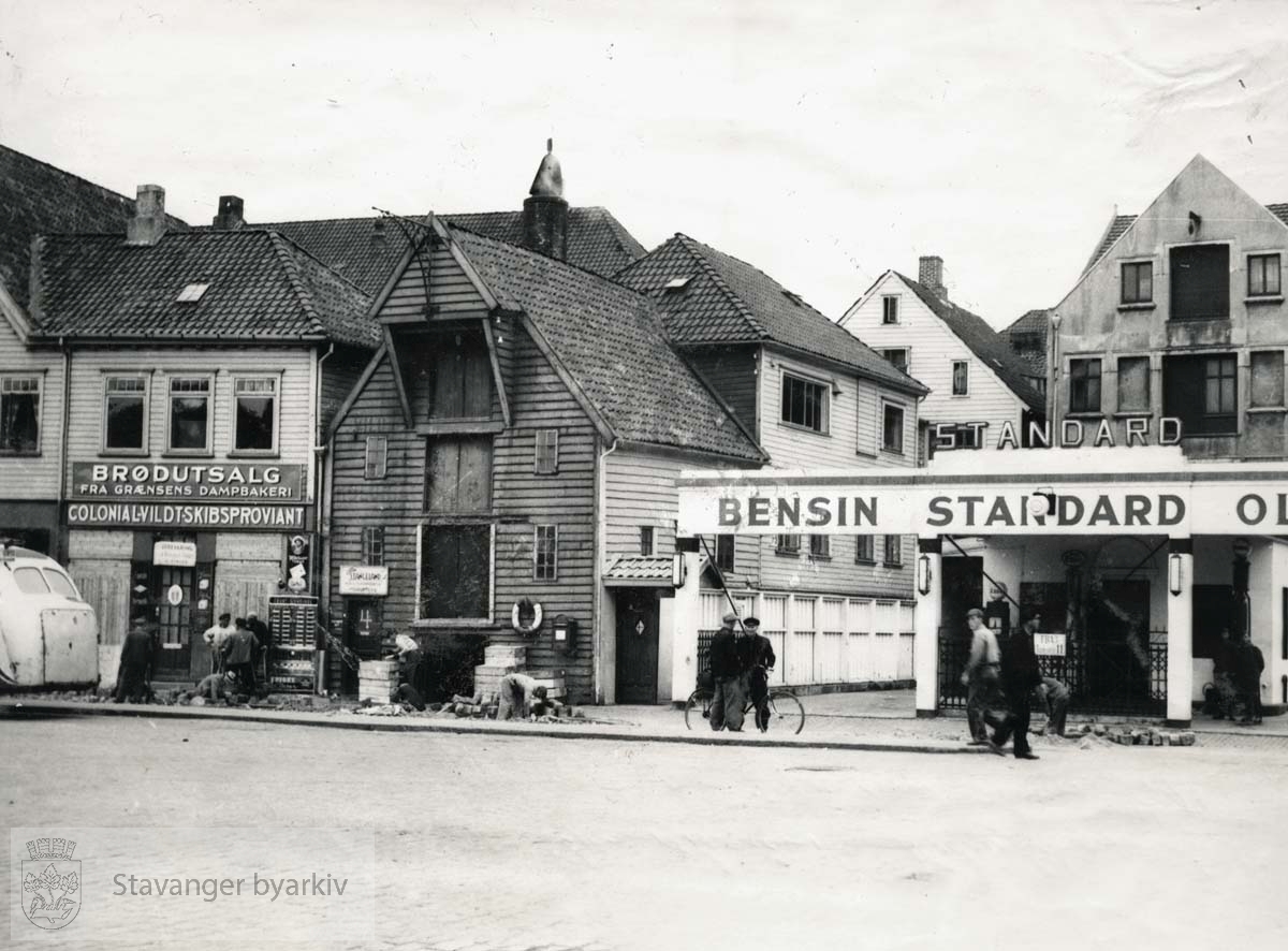 Nedre Strandgate 13 revet og gjenoppbygget av tyskerne i 1941. Brødutsalg til venstre. Bensinstasjon til høyre.