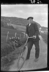 Portrett av en mann med sykkel, fotografert på en vei på Gry
